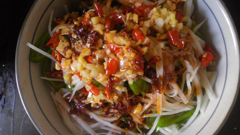 凉拌酸辣土豆丝,最后将炒好的香料和调好的汁一起倒入到土豆青椒丝碗内，搅拌均匀即可开吃