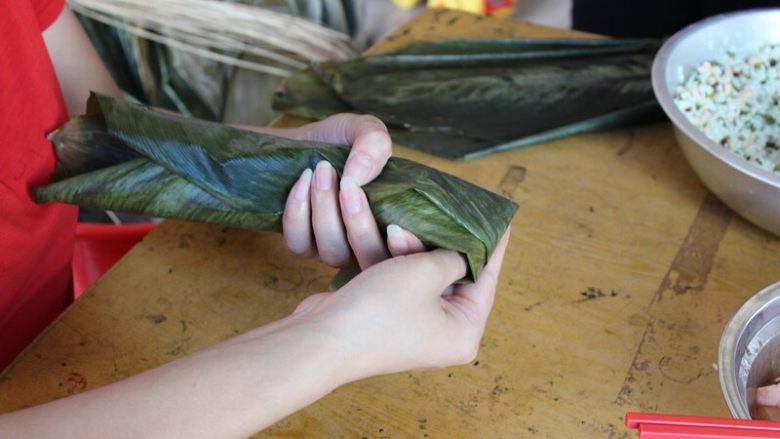 广式香菇花肉粽子（超详细，两种办法）,（长形粽子）右手把前方的粽叶往底部收