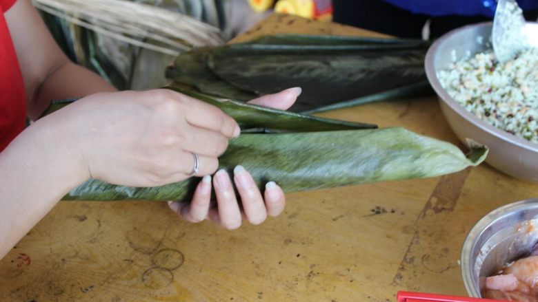 广式香菇花肉粽子（超详细，两种办法）,（长形粽子）左右两边的粽叶往中间叠，完全包住内馅