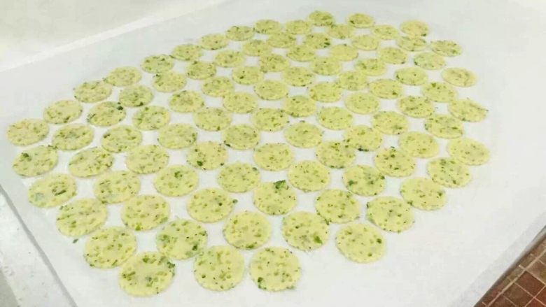 香葱芝士薄脆饼干,将4部分的面团放在高温垫上压成3-4mm的厚度，后放冰箱冷冻至稍硬后取出，用圆形饼干刻模刻出形状后放入烤盘内。