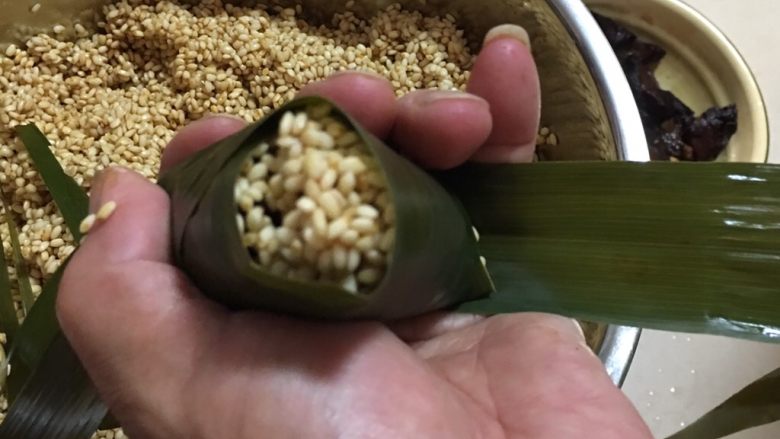 端午肉粽,盖住后还会有个小口,再取一片粽叶,一段垫在底部