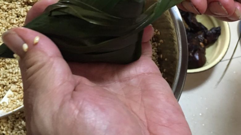 端午肉粽,再把叶子尾部攒在一起,顺着粽子的形状绕一下