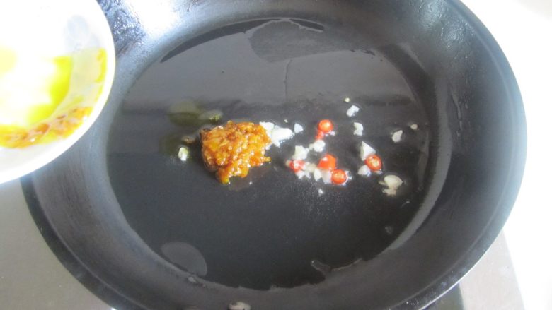 酸汤肥牛,烧热锅, 放入少许油, 下入黄辣椒酱和葱姜蒜末翻炒;