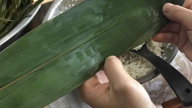肉粽子,开始包粽子啦,首先两片粽子叶叠在一起,一片叶子的根部和另外一片顶部放一块