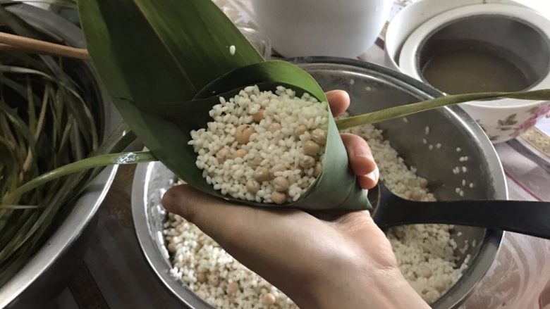 肉粽子,放完糯米后,用棕叶的叶尖夹在两片粽子叶的中间,冒出来的棕叶尖不要太长