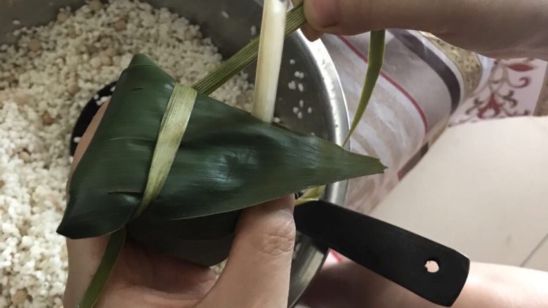 肉粽子,棕叶的中间部分围着粽子绕圈,一定要勒紧,绕三圈就可以