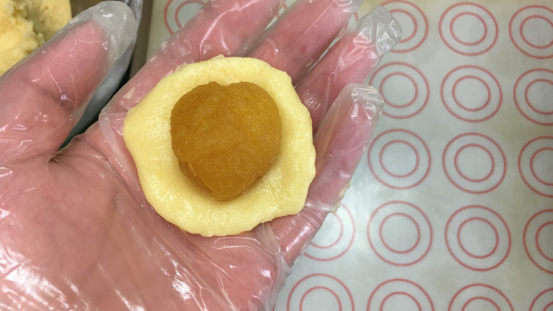 凤梨酥,我包凤梨酥用的皮是21克左右,凤梨馅是15克左右。取一块面团按圆,然后加入凤梨馅。