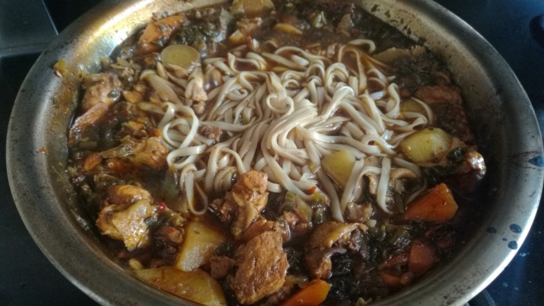 一鸡两吃之小公鸡三步走,另起一个过下面条,将煮熟的面条沥干水分放入炒鸡的锅中,拌着吃。