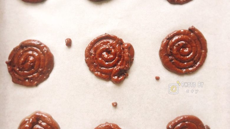 像棒棒糖的巧克力豆曲奇饼干,烤盘上铺好油纸,用裱花袋挤出棒棒糖曲奇的模样,中间稍微间隔开来。
烤箱上下火180度预热,中层烤12分钟左右。
