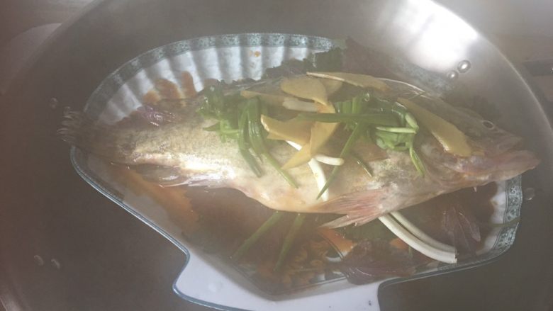 清蒸桂鱼,腌制的葱姜柠檬等去腥调料去掉,换上新葱姜调料,淋上蒸鱼豉油,植物油,放入锅中,隔水蒸。