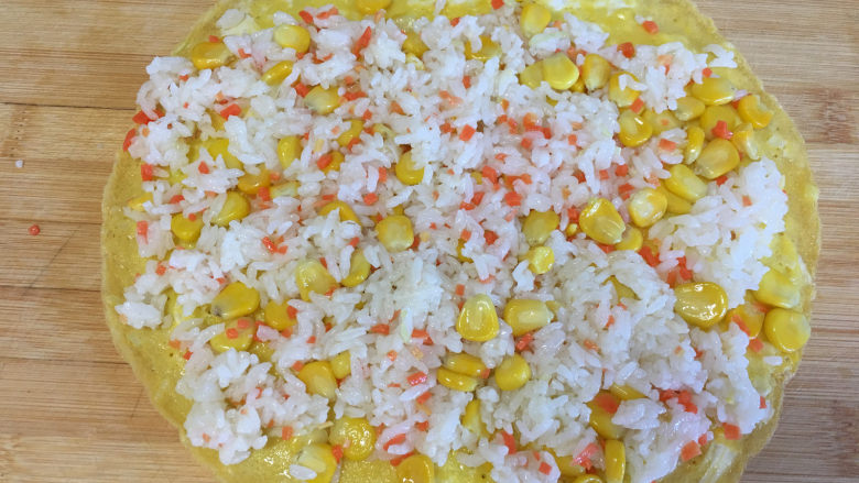 早餐鸡蛋卷,将煎好的蛋饼放在案板上,表面铺上什锦饭,用手将什锦饭压一下。