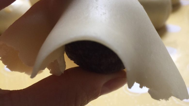 没错,高筋粉也能做蛋黄酥,用一只手按着豆沙馅儿,把面片翻转过来。另一只手往下轻轻的捋面片,让面片都垂直,并尽可能的贴着豆沙馅