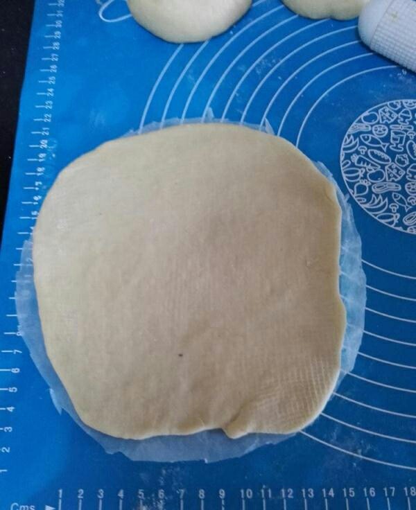 网纹红豆面包,剪一块和八寸圆模差不多的油纸,将擀卷好的面团放到油纸上面。