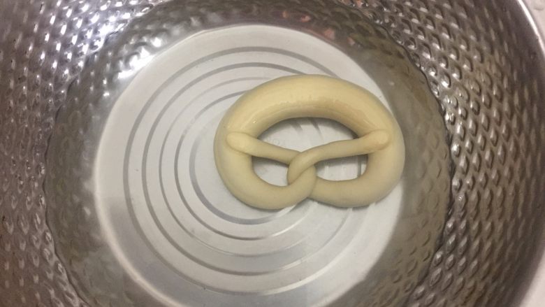 德国碱水面包普雷结,冷冻好后戴手套把面团在碱水中浸泡20秒,反面也泡20秒捞出