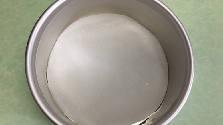8寸芒果慕斯蛋糕,将剪好的圆形油纸铺在蛋糕模具底部。