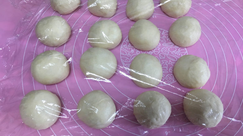 肠仔面包卷,取出面团进行排气,然后平均分成16份,滚圆后盖保鲜膜醒发10分钟。