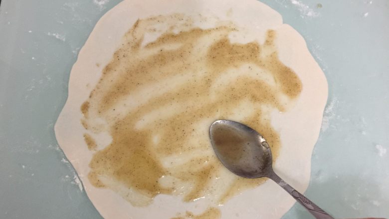 培根葱油饼,取一个面团擀开成薄片,抹上适量油酥