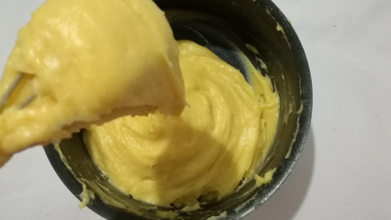 草莓泡芙,直到蛋液用完,提起打蛋器,面团呈倒三角状即可。烤箱预热上下火210度15分钟。