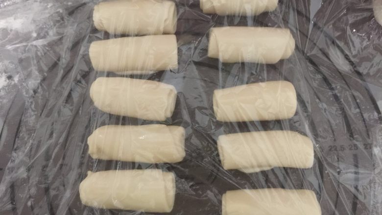 莲蓉蛋黄酥,再取一个卷换个方向压扁擀长卷起,用保鲜膜盖好松弛20分钟