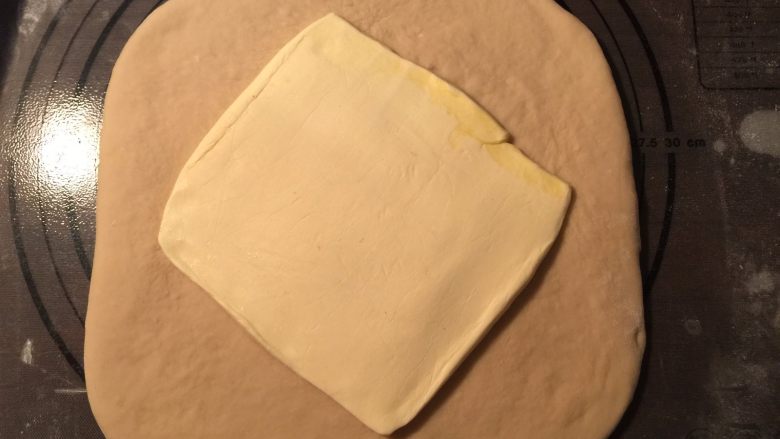 流沙起酥包,冷藏好的面团取出擀成长方形,黄油薄片放在中央