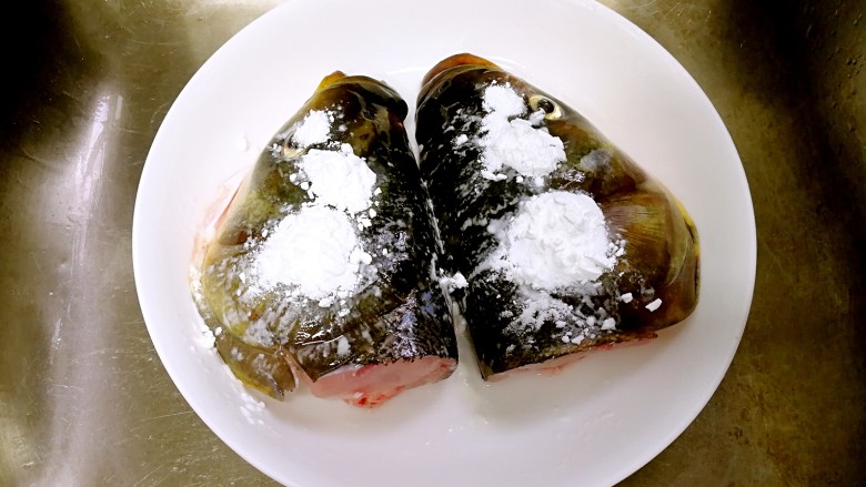 蒜香豆豉蒸鱼头,撒一点生粉,在表面抹匀,冲洗干净。