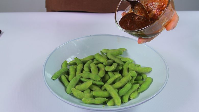 麻香酸辣毛豆,将调好的酱汁倒入毛豆里搅拌