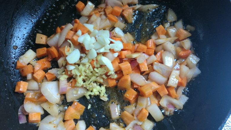 剩米饭华丽大变身——虾仁焗饭,接着放入红萝卜丁,翻炒两下,放入蒜片姜末翻炒均匀。