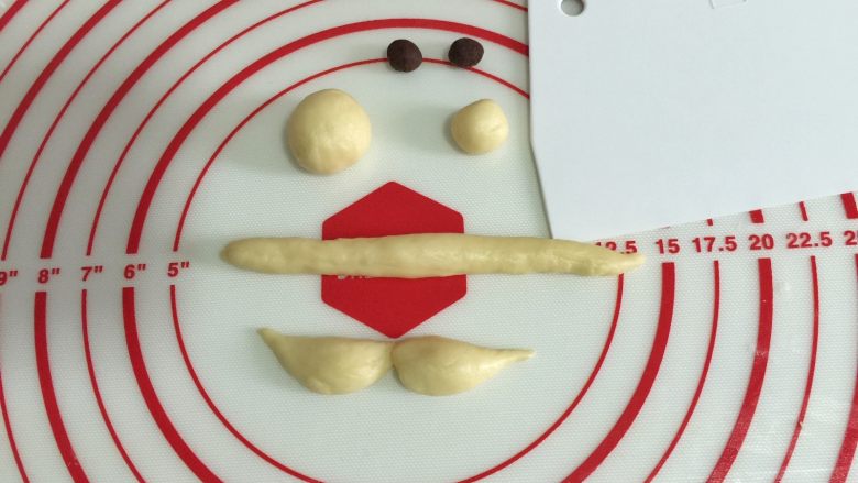 圣诞老人面包,剩下的面团分割为15克帽沿、7克帽球、2克鼻子、5克胡子。两个眼睛分别约1克,加入<a style='color:red;display:inline-block;' href='/shicai/ 920'>可可粉</a>揉匀后称重。