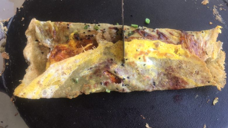 正宗天津煎饼果子,用铲子在中间 插一下,不要完全插断,把薄脆插断就好。