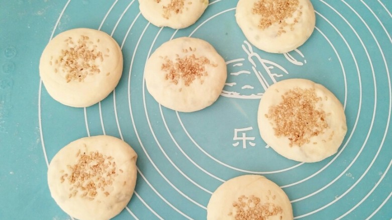 香葱芝麻油饼,表面刷上一层清水,撒上适量芝麻,按压一下,以防漏芝麻。