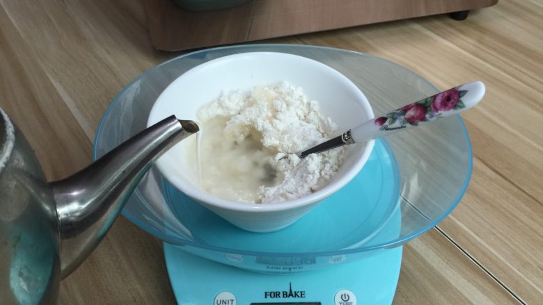 肉松花环面包,先将面粉用烧至沸腾的开水冲进高筋面粉中,迅速搅拌均匀,以免有面疙瘩,将其晾凉备用(也可提前一晚做好放冰箱第二天用)
