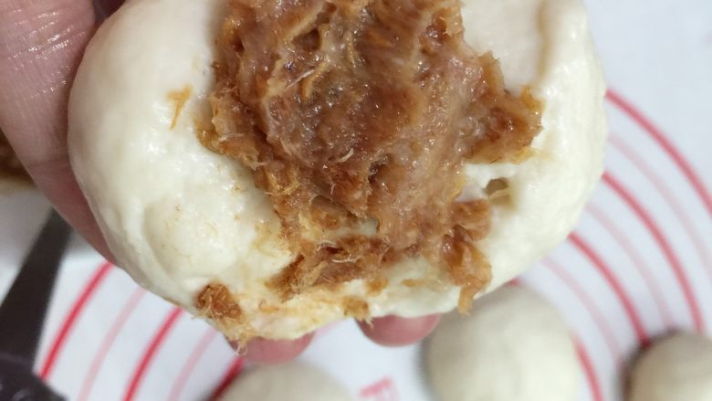 肉松花环面包,把松弛好的面团按压开,取适量的肉松