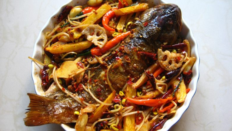 川香麻辣烤鱼:麻辣过瘾的豪华烤鱼,在装鱼的烤盘中先放入香菜,再依次放入煮好的干豆腐、豆芽、炸好的土豆、莲藕、连同煮料汤一起倒入烤盘中,汤汁最好多一些,以漫过鱼的1/2处为佳。