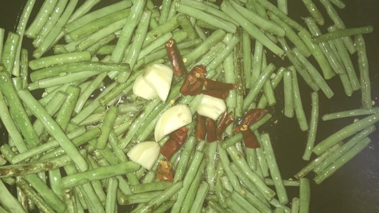 干煸豆角,煸炒至豆角转色，加入蒜头干辣椒