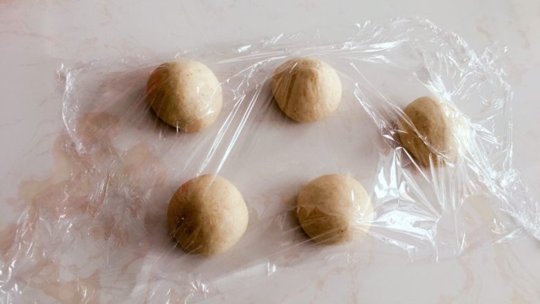 高纤低脂的全麦蔓越莓贝果,滚圆后盖保鲜膜醒10分钟。
盖保鲜膜是防止面团表面丧失水分变干。醒面是为了修复切断的面筋,也会让面团柔软易整形。