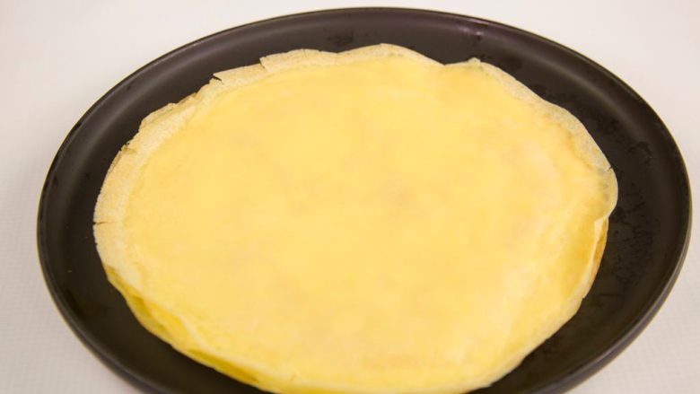 香蕉可丽饼,舀一勺面糊平铺在锅底,同一方向迅速转动平底锅,到面粉糊完全覆盖住锅,底开小火煎至金黄色,有气泡出现时说明饼皮已经熟了,放在晾架上冷却待用。