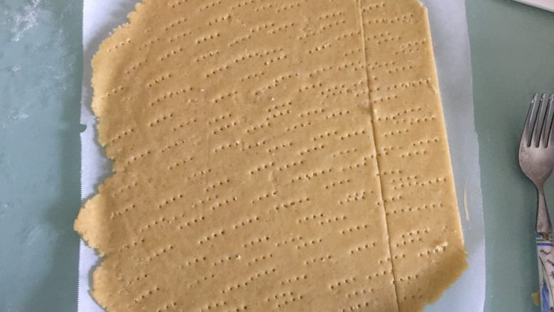 海苔咸味饼干,案板上撒一薄层低筋面粉或者上下各铺上一层油纸,把松弛好的面团放在案板上擀开成薄面片,用叉子在表面扎点小孔