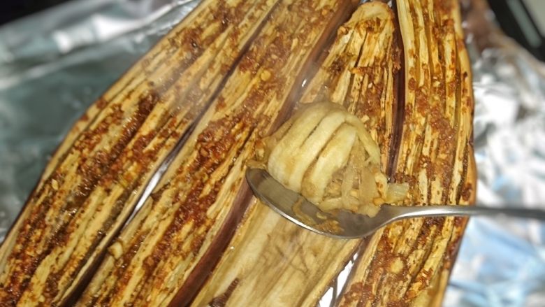 烤茄子,茄子取出,用勺子刮出茄肉,将葱油拌入茄肉里