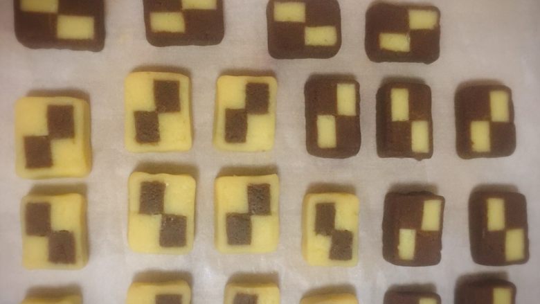 双色格子/棋盘饼干,同样的方法也把可可面团的边角料包裹格子条,切成片。还有一条格子条直接切片。把切片都放在铺了油纸的烤盘上