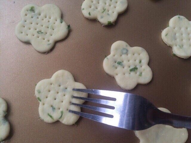 胡萝卜香葱爱心饼干,把印好的小饼干全部放入烤盘中，然后用叉子或牙签压出小孔。