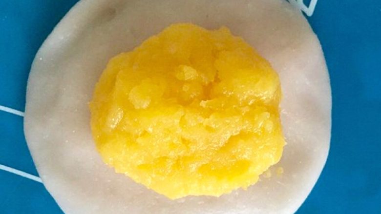 Q弹奶黄冰皮月饼,冷却好的奶黄馅平均分成12个奶黄馅团,将一个奶黄馅团包进冰皮里。(整体大概50g,刚好用50g的月饼模具)