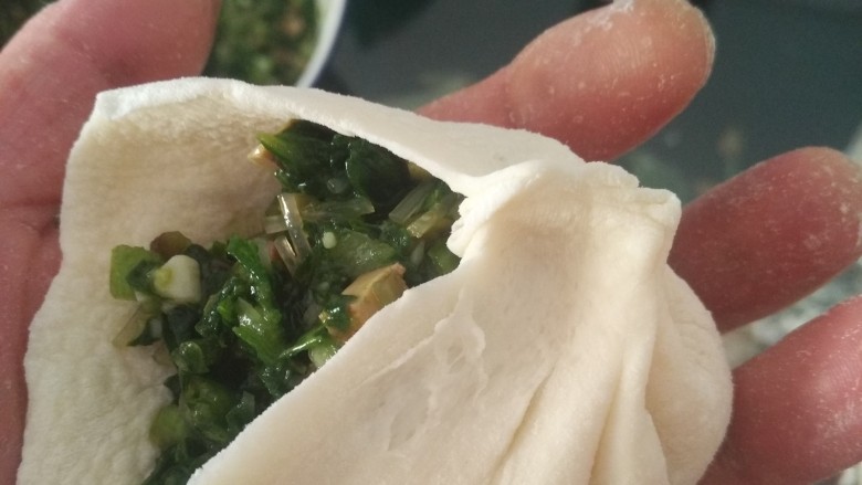 青菜香菇包,左手心微微下弯,用右手的拇指和食指捏住面皮一侧并往上提形成第一个褶子,松开右手食指把褶子和面皮捏在一起 ,用左手食指把旁边面皮推向右手食指的位置并捏紧,形成第二个褶子,以此类推逆时针捏直至最后一个褶子,最后收口捏紧后轻轻扭一下,一个包子做好了。
