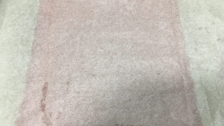 红丝绒旋风蛋糕卷,从烤盘中取出放在晾网上晾凉,表面盖一张油纸。
