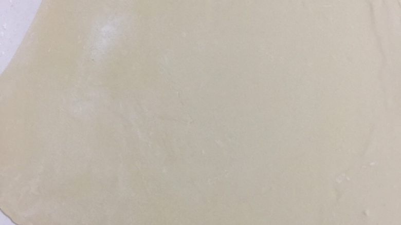 椒盐葱油饼,案板上撒少许面粉，面团用擀面杖擀成薄片。