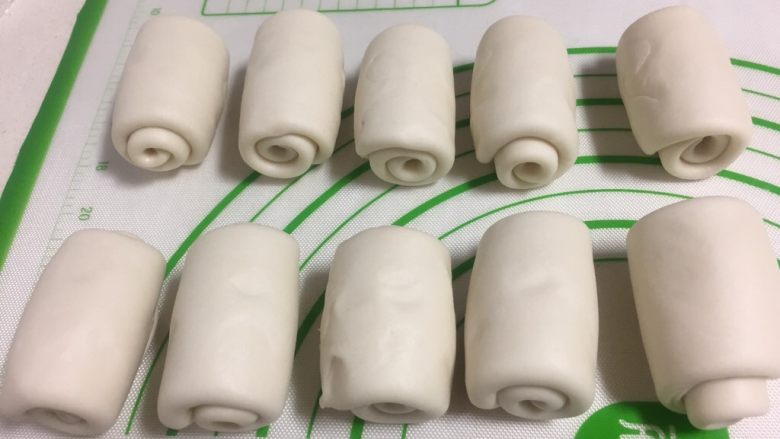 酥皮点心紫薯酥,重复上面的工作,收口的地方朝上擀成牛舌状,自下而上推卷起来,收口朝下盖保鲜膜静置15分钟。