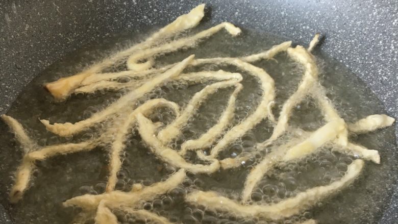 椒盐味干炸杏鲍菇,锅里放入油,油温七成热的时候,把菇一条条放入锅中