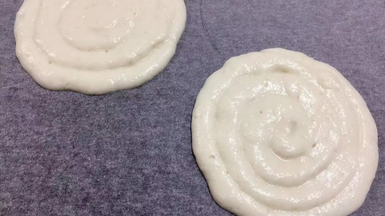 芒果馬斯卡彭芝士蛋糕,裝入圓嘴裱花袋中 在烘焙紙上擠螺旋形圓餅漿x2個(這個大小要比畫的圓小約1寸 不然成品會影響外觀)