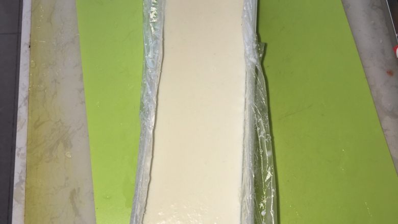 椰丝牛奶小方,把融化的吉利丁放入锅里,搅拌至融化,可以稍微再加热,但不能煮沸,否则影响吉利丁的凝固效果。放凉的奶液倒进盒里。