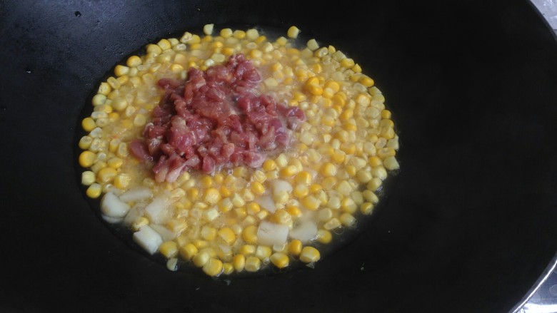 玉米青红椒炒肉丁,加入瘦肉丁炒一下,盖上锅盖煮五分钟左右。