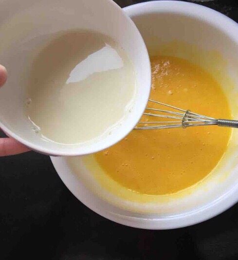 豆乳盒子蛋糕,3.蛋黄加入20克砂糖、黄油40克,用手动打蛋器搅拌均匀后倒入40毫升豆浆,继续搅拌均匀。
